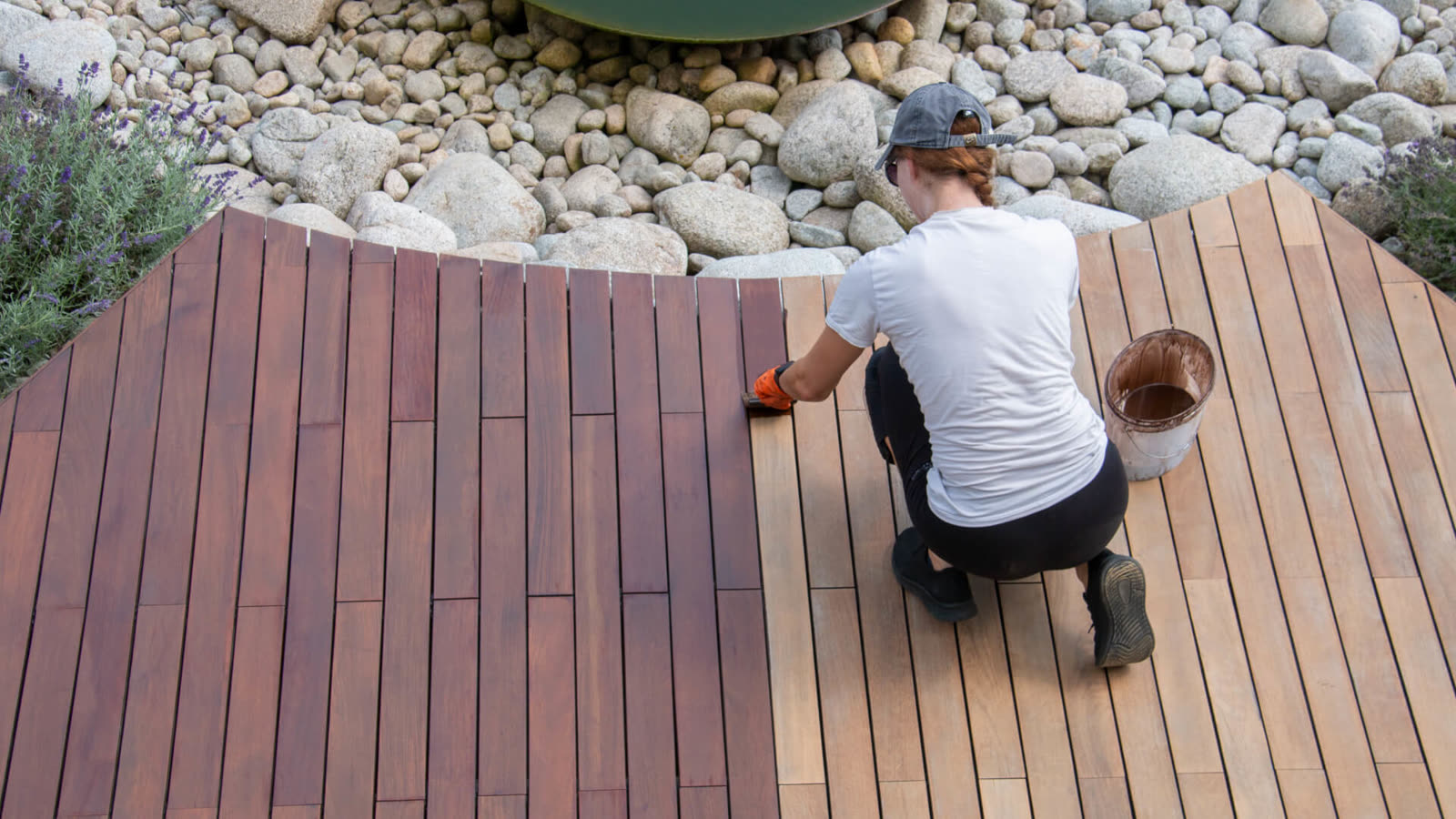 Vlonder oliën door Vlonderhoud Vlonderolie wordt met kwast aangebracht op een hardhouten vlonder in de tuin — warme kleur en waterafstoting keren terug